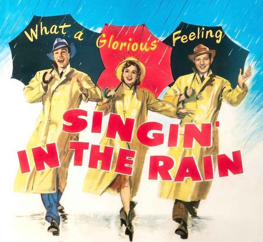 Singing in the Rain vintage movie poster with three people in yellow raincoats holding umbrellas